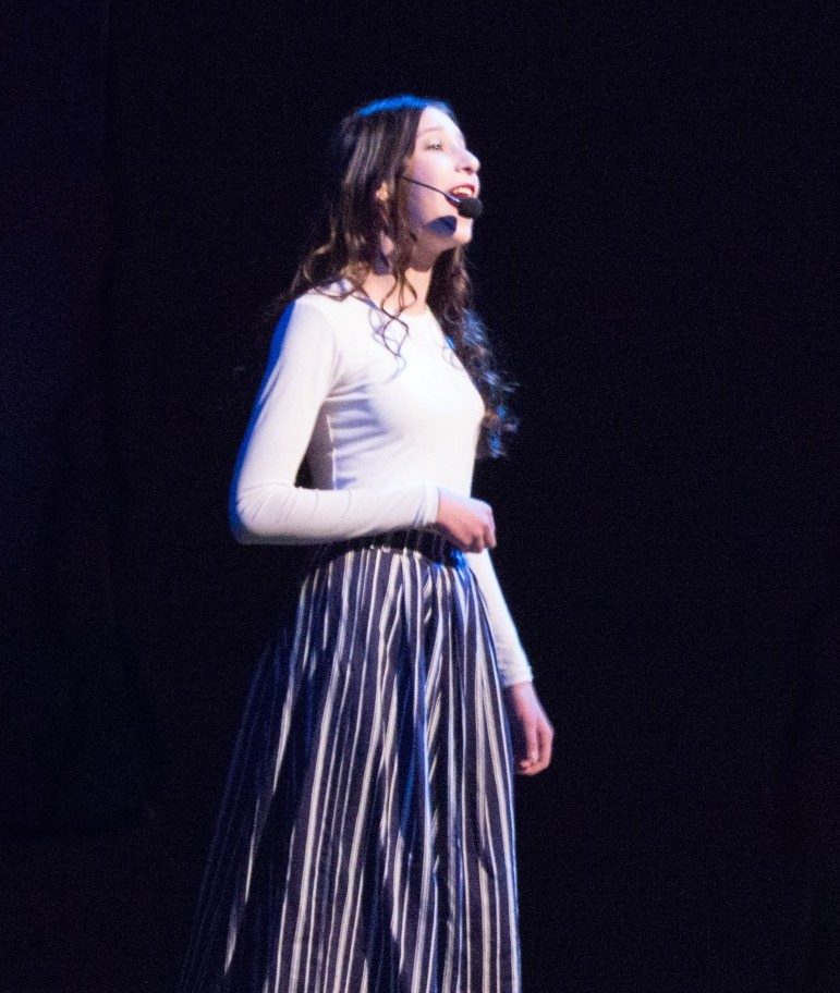 A student singing a solo under blue stage light
